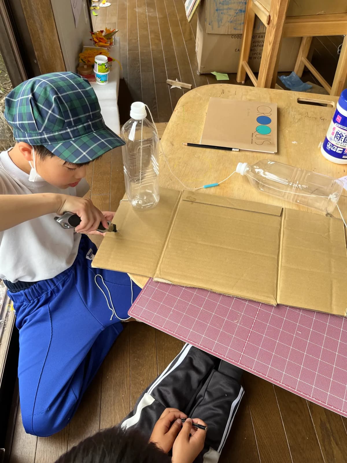 段ボールとペットボトルで工作するこども