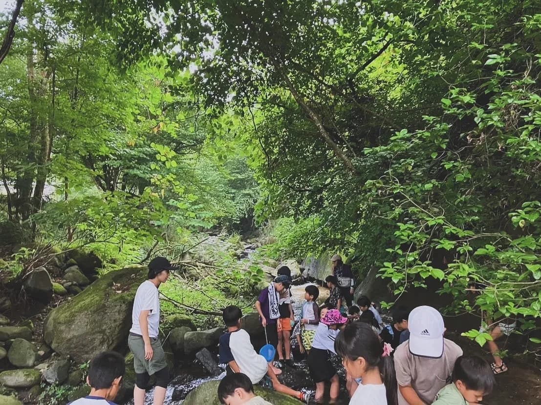 大人と一緒に川で探検するこどもたち